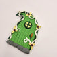 The Elvish fairy door sits at an angle on a white background. Shaped like a leaf, this Elvish door has green wood patterning, white vine finish, and a window. It is detailed with yellow flowers.